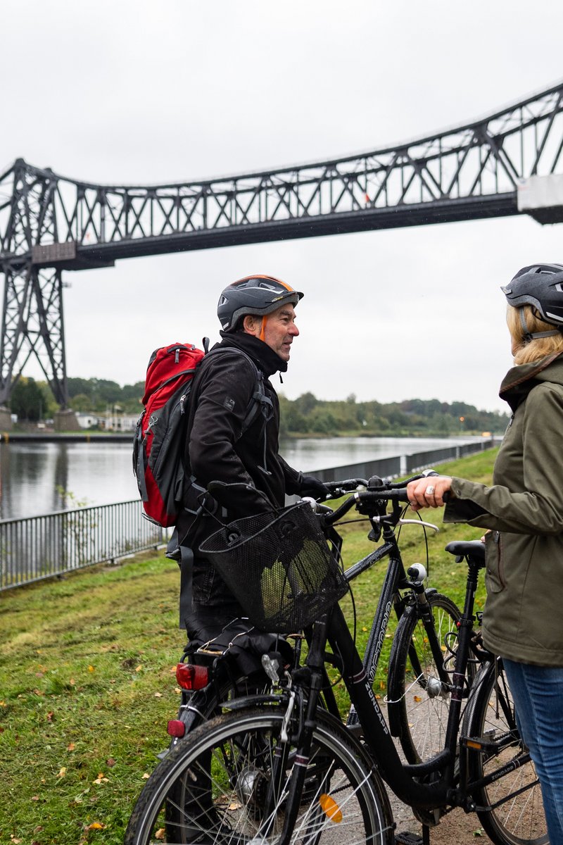 Zwei Radfahrerinnen vor einer Brücke über den NOK