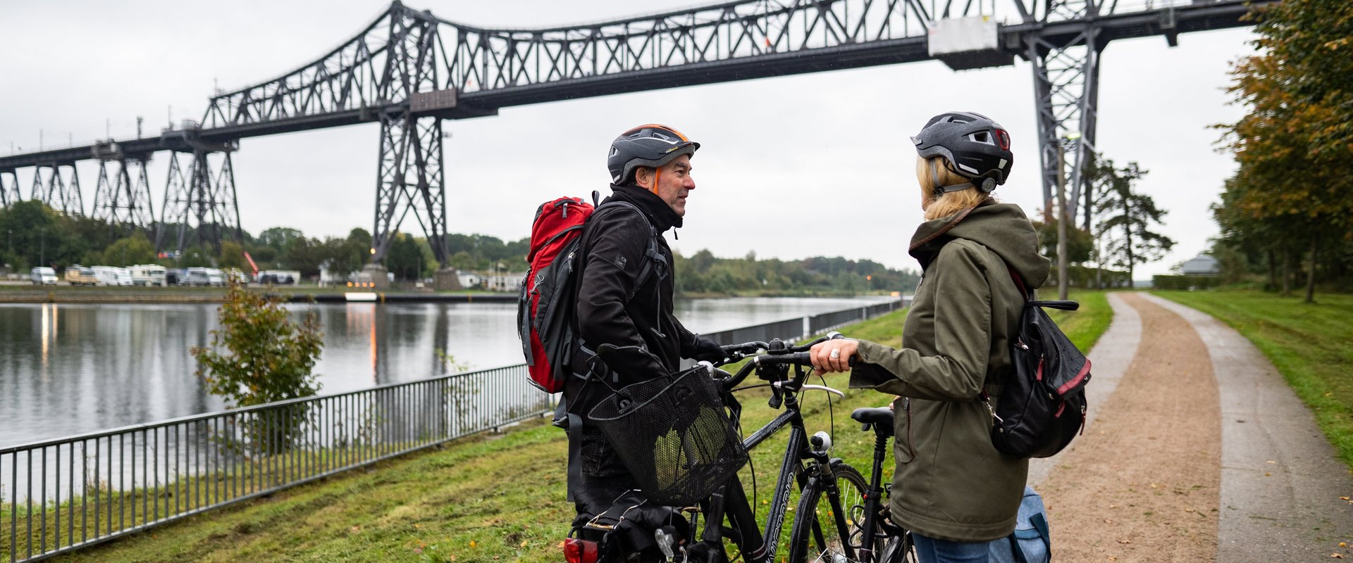 Zwei Radfahrerinnen vor einer Brücke über den NOK