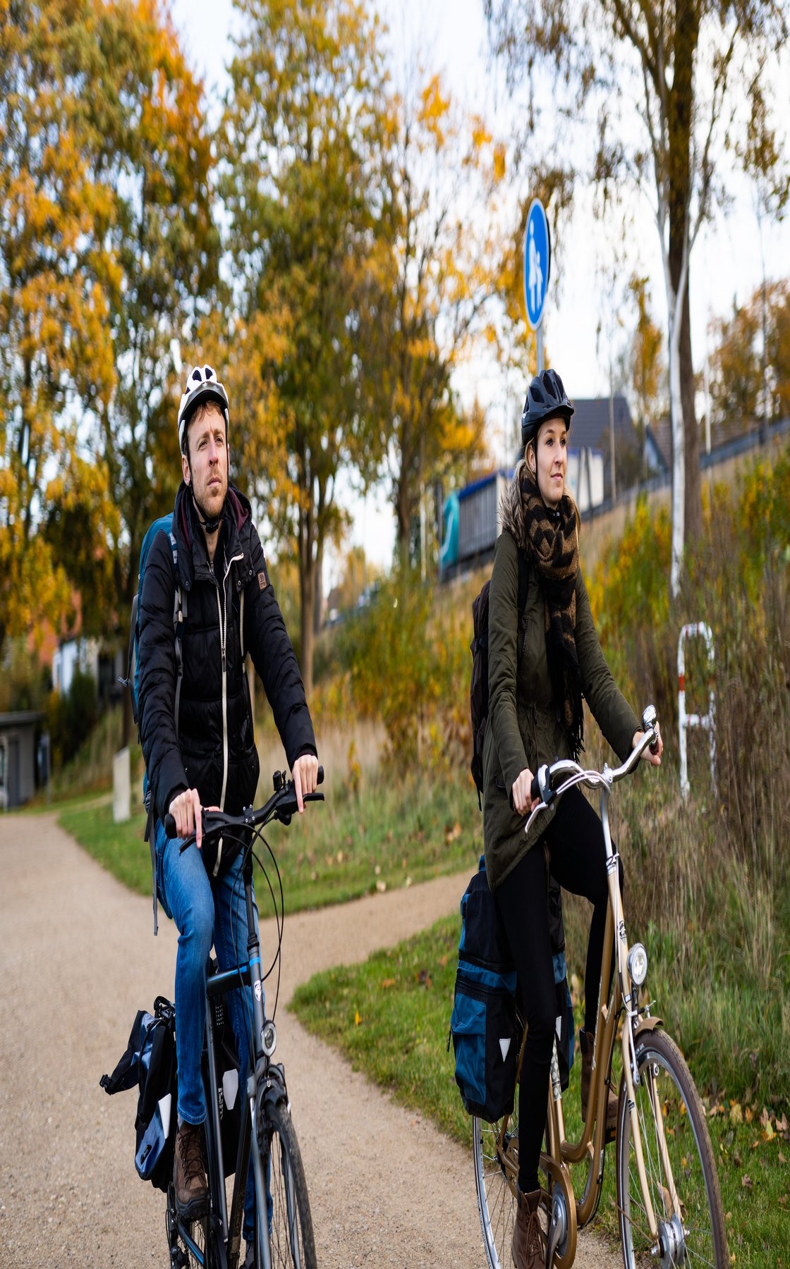 Zwei Radfahrerinnen neben Bäumen mit Herbstfärbung