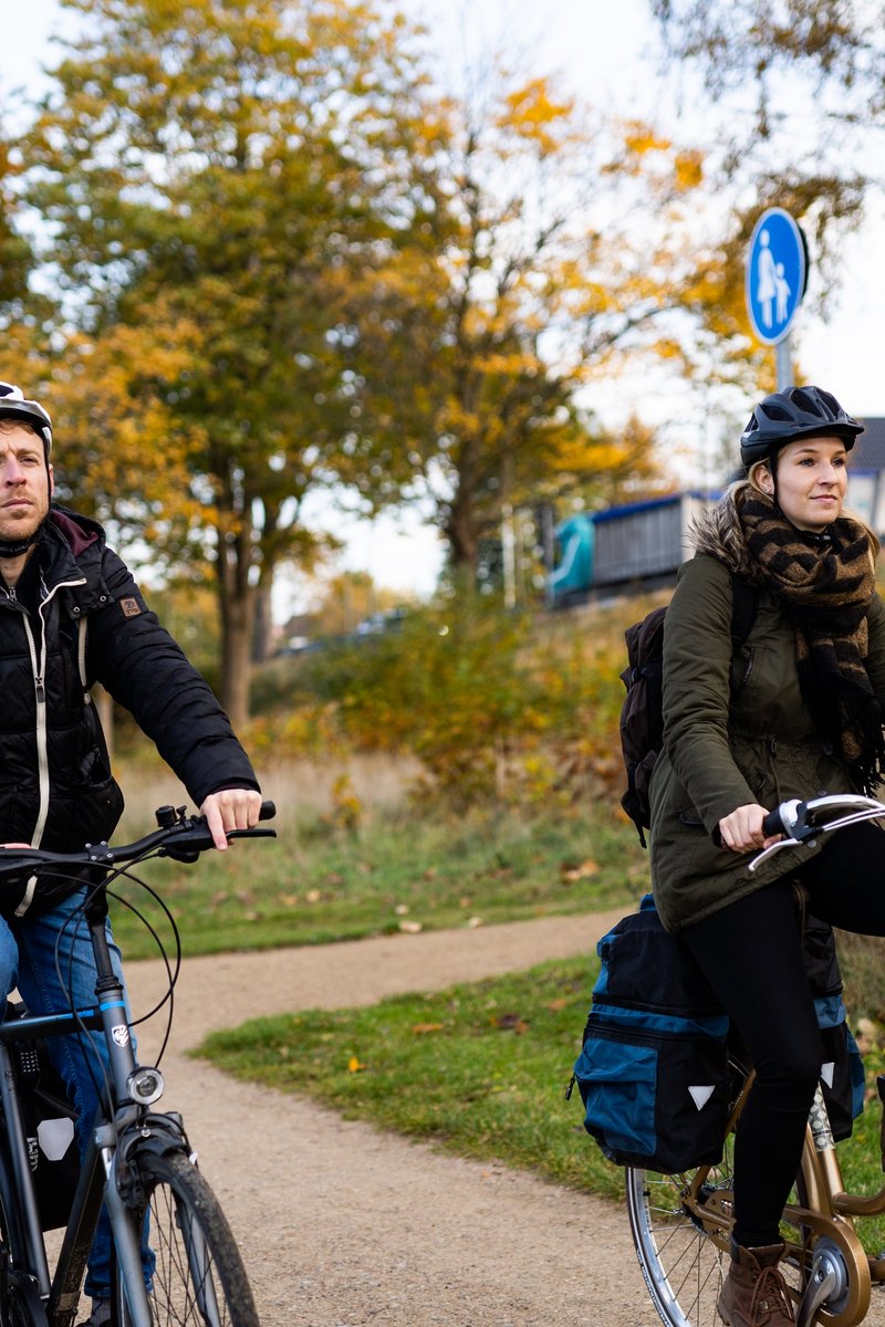 Zwei Radfahrerinnen neben Bäumen mit Herbstfärbung