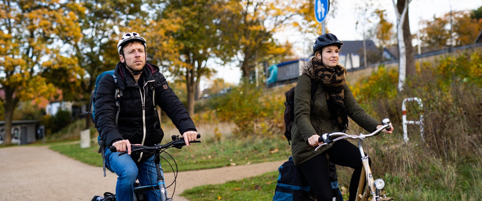 Zwei Radfahrerinnen neben Bäumen mit Herbstfärbung