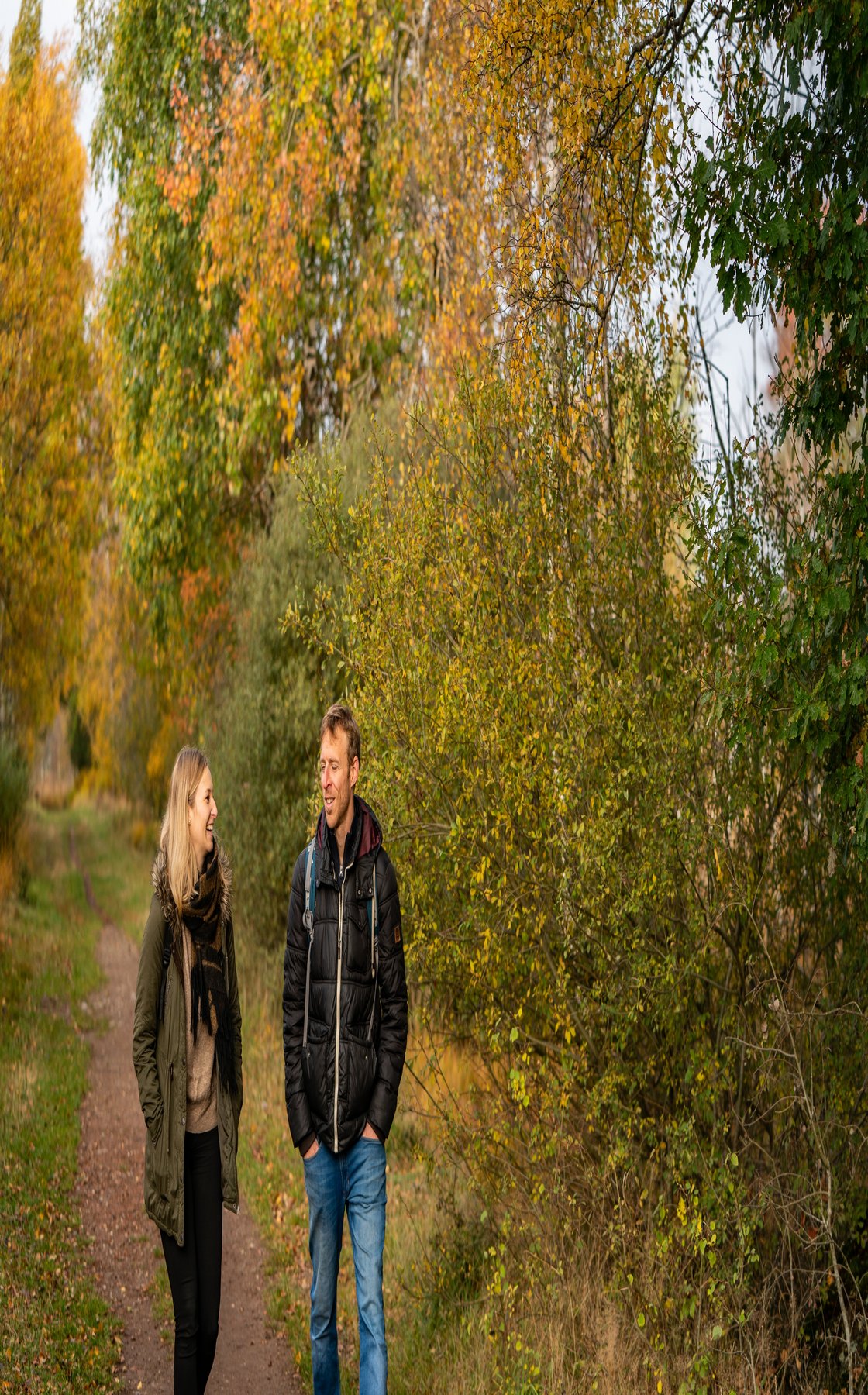 EIn Prächen geht im Herbst durch einen bunt gefärbten Laudwald