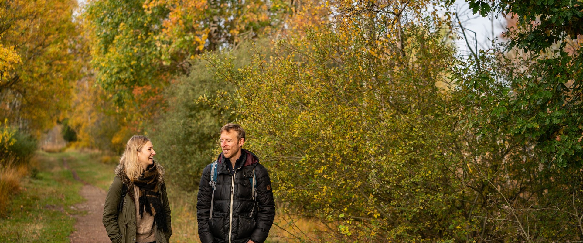 EIn Prächen geht im Herbst durch einen bunt gefärbten Laudwald