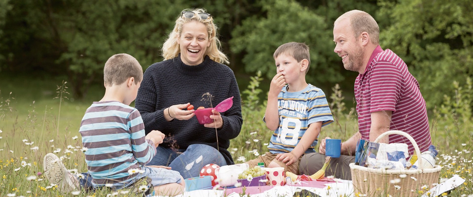 Eine Familie sitzt zum Picknick auf einer Wiese